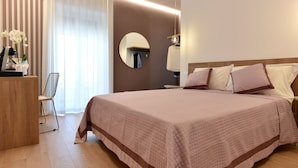A neatly arranged hotel room with a large bed, a bedside table, a mirror, and a chair. - Dimora al castello (Matera)