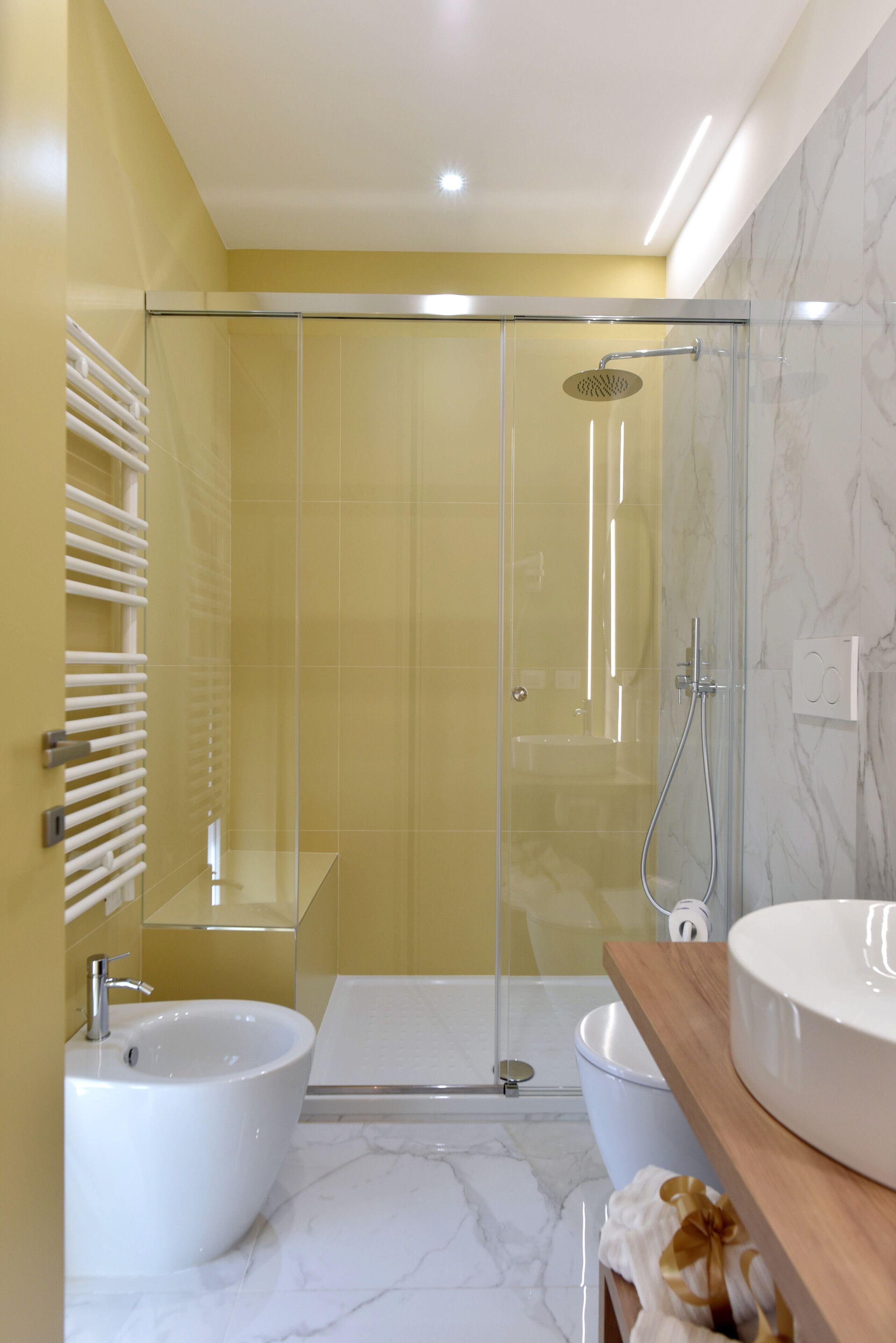 A modern bathroom with a glass-enclosed shower, a white sink, and a marble-tiled floor.