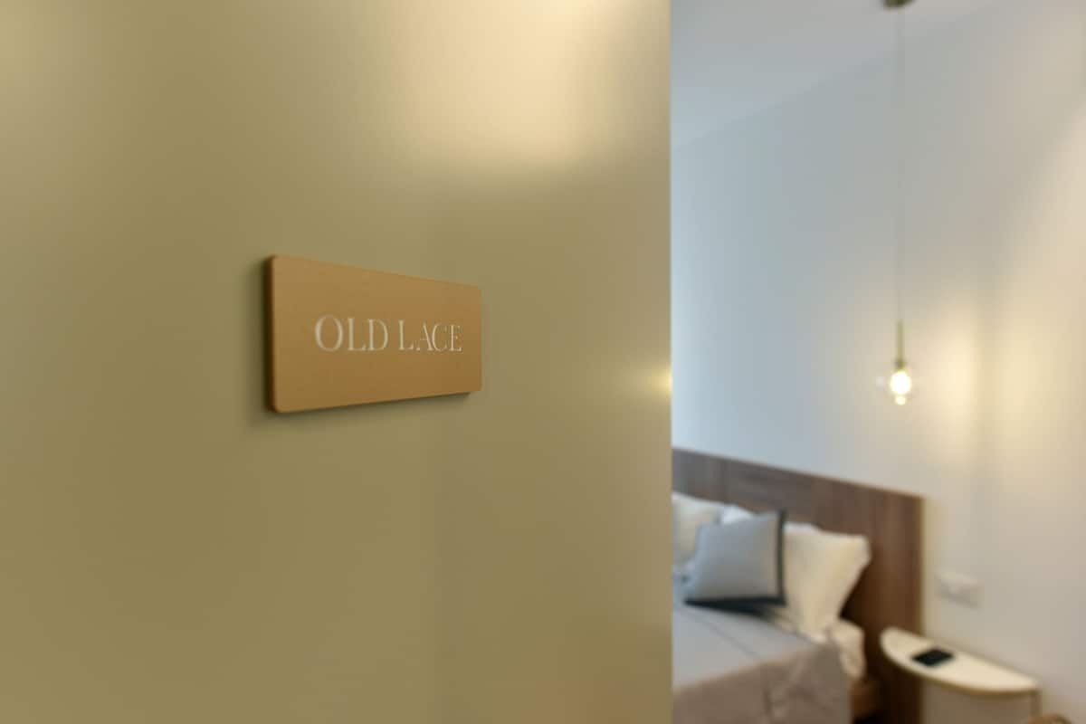A hotel room with a bed, a nightstand, and a hanging light fixture.