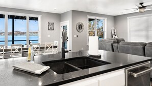 A modern kitchen with a large island, white cabinetry, and a view of the water. - BARE FEET RETREAT! Swim Dock, 5 Decks, Elevator, Gaming Room, Bagnell Dam Strip! (Lake Ozark)