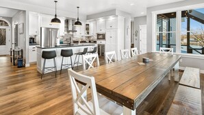 A modern kitchen with white cabinets, a wooden island, and bar stools. - BARE FEET RETREAT! Swim Dock, 5 Decks, Elevator, Gaming Room, Bagnell Dam Strip! (Lake Ozark)