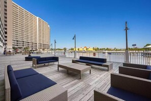 A rooftop terrace with outdoor seating, a view of a tall building, and a clear sky.