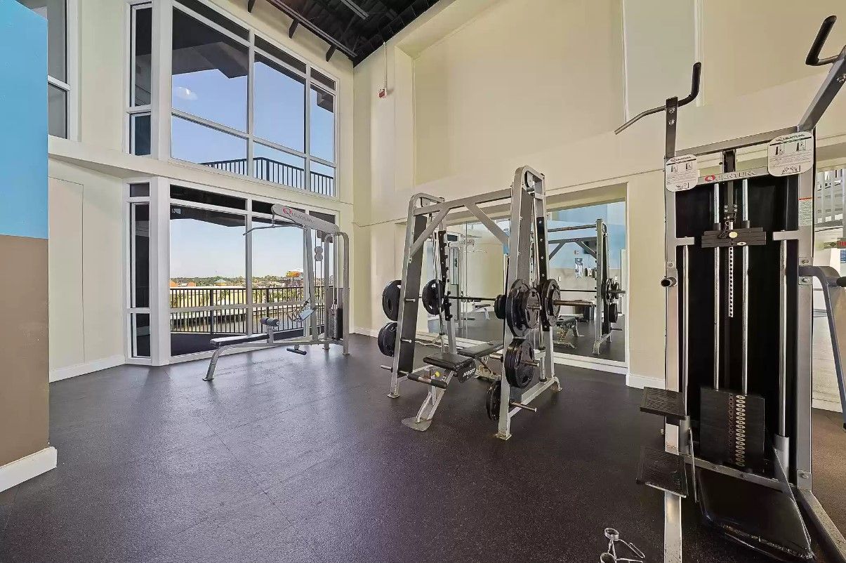 Una palestra con attrezzature per sollevamento pesi, ampie finestre e vista sull'esterno.