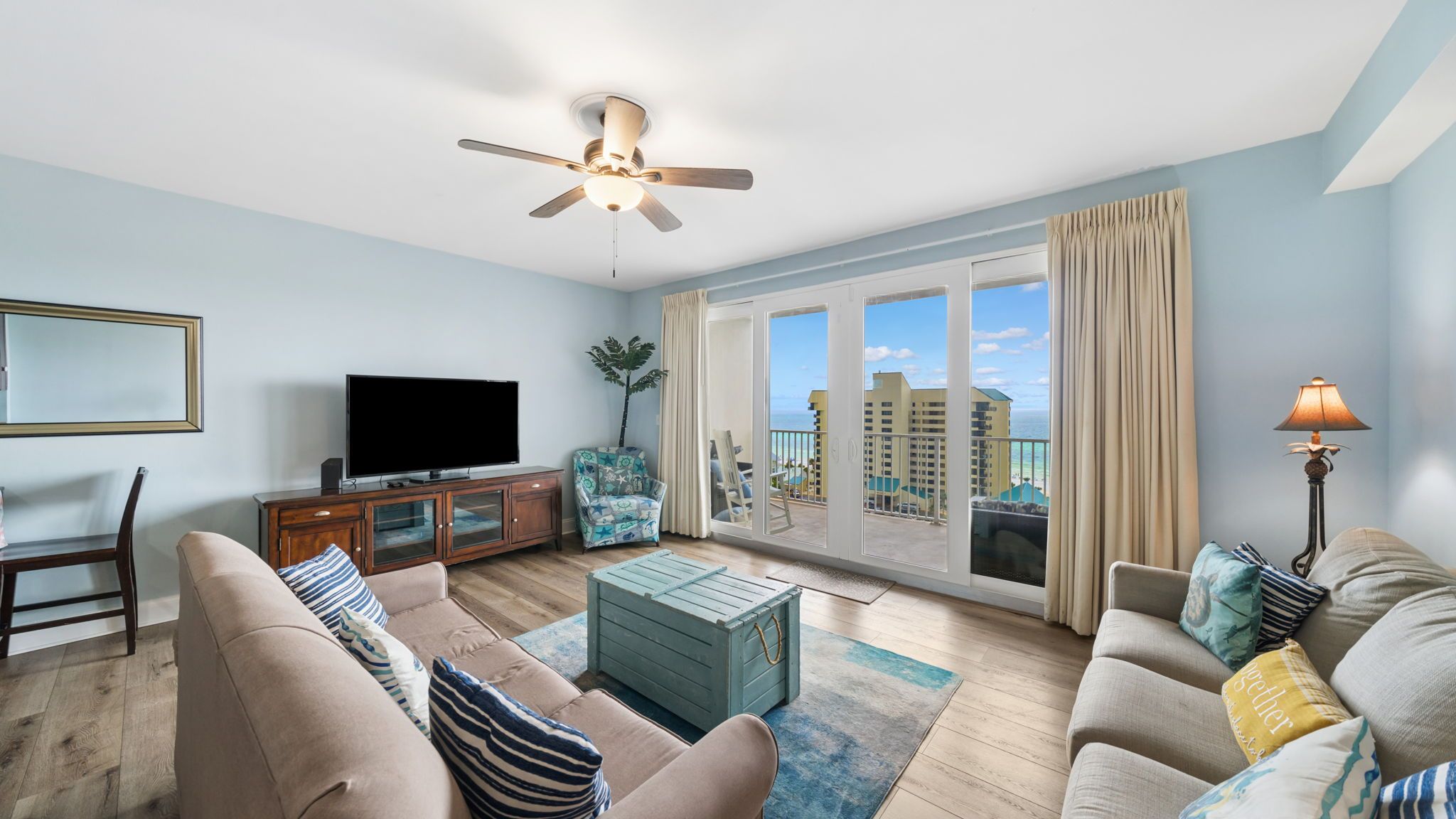 A living room with a television, sofas, a coffee table, and a ceiling fan.