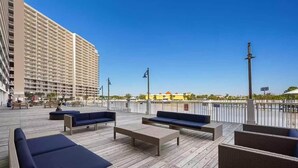A rooftop deck with outdoor seating, a tall building in the background, and a clear sky. - Sand n Stars (Panama City Beach)