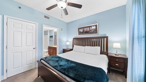 Un dormitorio con cama, mesita de noche, ventilador de techo y puerta.