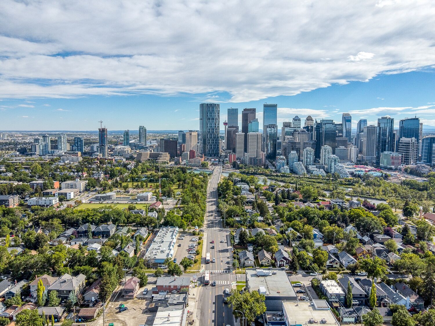 Un paysage urbain avec des immeubles modernes de grande hauteur, un mélange de quartiers résidentiels et un ciel dégagé.