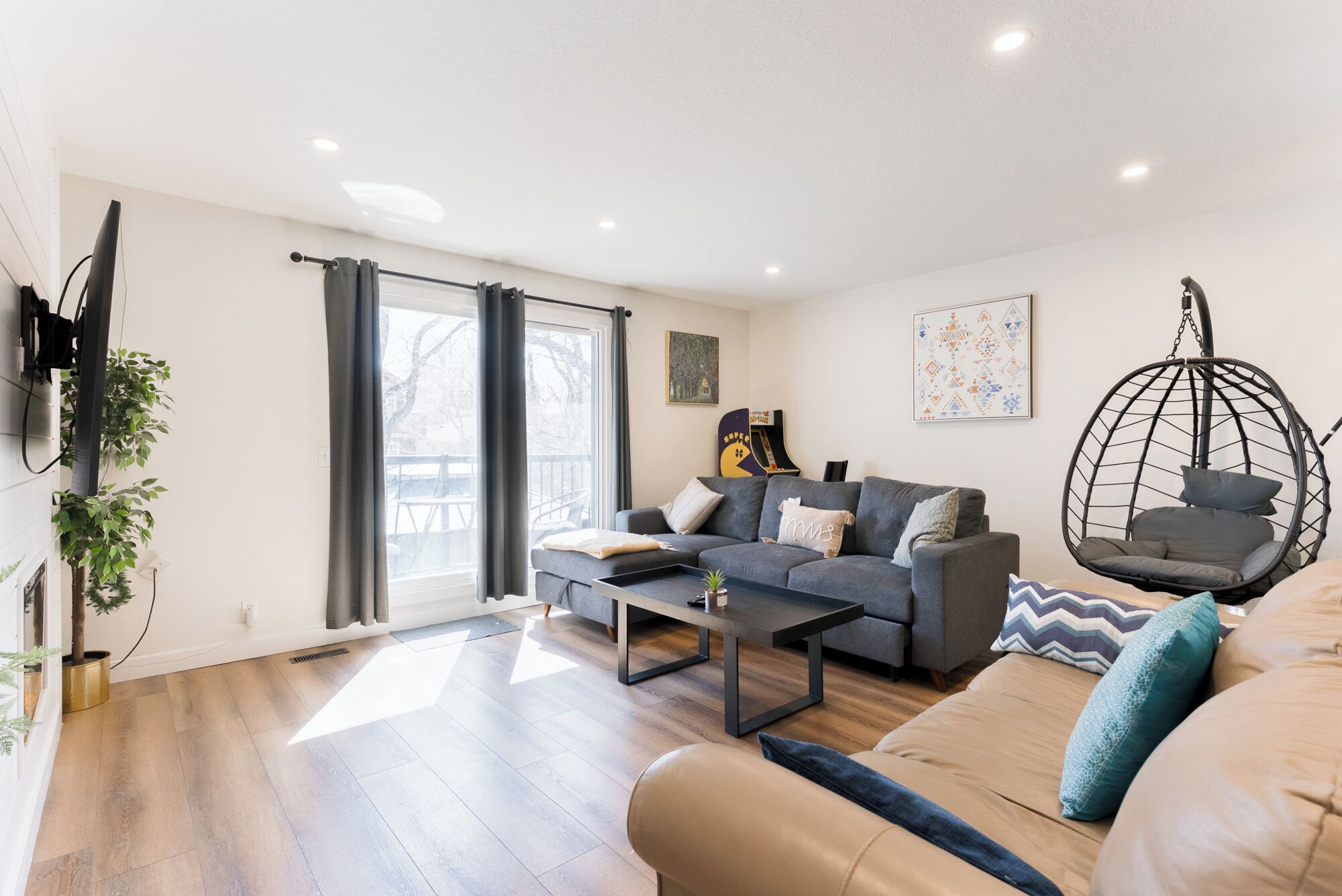 Un salon moderne avec un canapé, une table basse et un fauteuil suspendu.