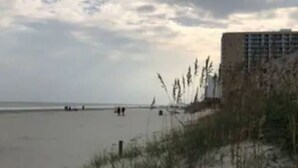 Una playa con un edificio al fondo.
