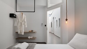 A modern hotel room with a bed, a robe, and a mirror. - Southrock Villas - 6 Bed Superb Seaview Villa with Private Pool (New Listing) (Lachania)