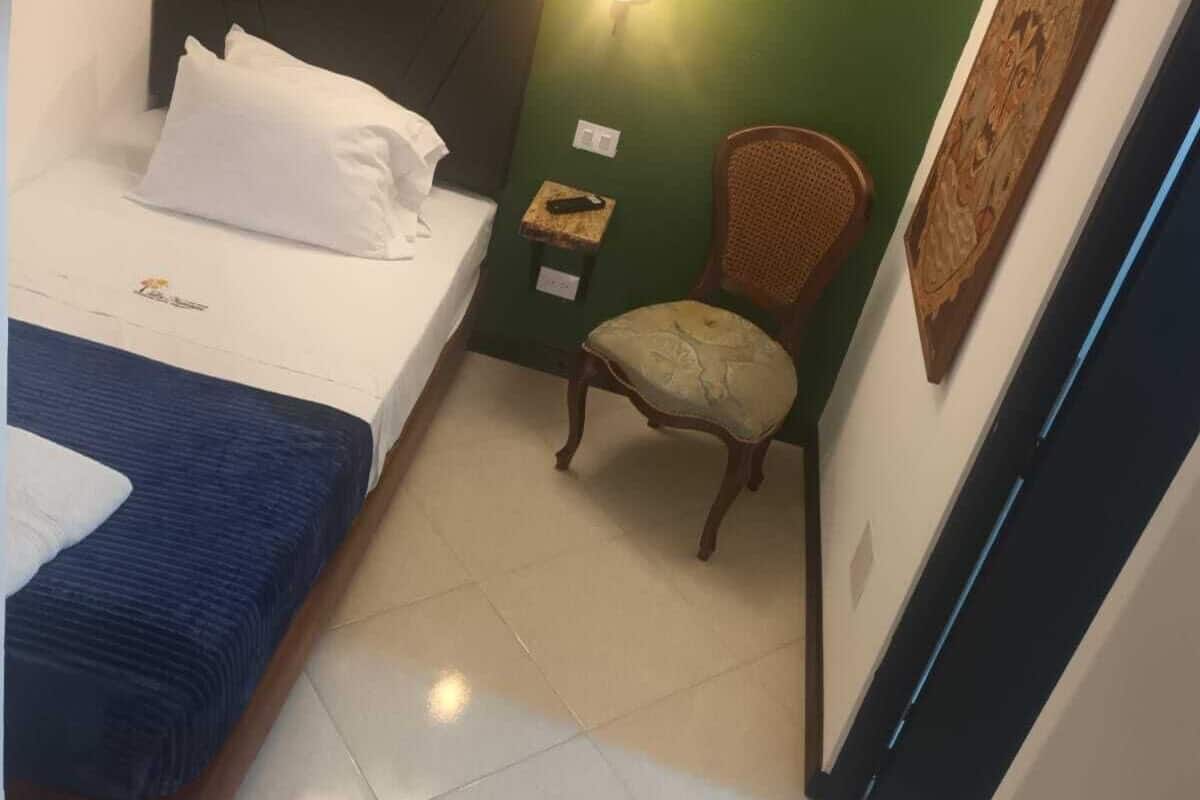 Une chambre avec deux lits, une chaise, une table de chevet et un luminaire fixé au mur.