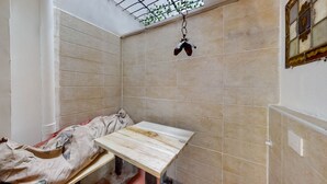 A room with tiled walls, a wooden bench, and a hanging plant.