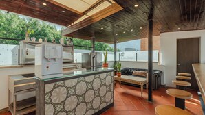 A modern kitchen with a central island, a seating area with a sofa and coffee table, and a view of the outdoors.