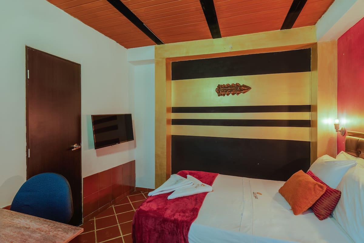 Une chambre d’hôtel avec un lit, une télévision, une moquette rouge et un plafond en bois.