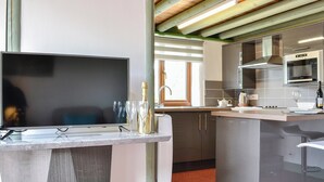 Eine moderne Küche mit Flachbildfernseher, Weingläsern und einer Champagnerflasche.