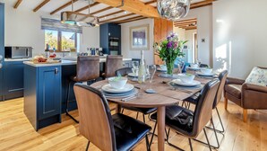 A modern kitchen with wooden beams, a central island, and a dining area with a round table and chairs.