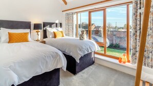 A modern bedroom with two beds, a large window, and a view of the outside.