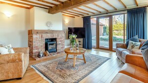 A living room with a fireplace, wooden beams, a sofa, a coffee table, and a TV.