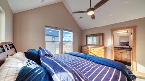 A bedroom with a large bed, a ceiling fan, and a view of the outside. - Midgarth Hus- Brand New PET FRIENDLY home minutes to Copper & Ski Cooper! (Leadville)