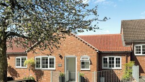 A brick house with a red-tiled roof, a front door, and a small fenced garden area. - 1 bedroom accommodation in Ledbury (Ledbury)