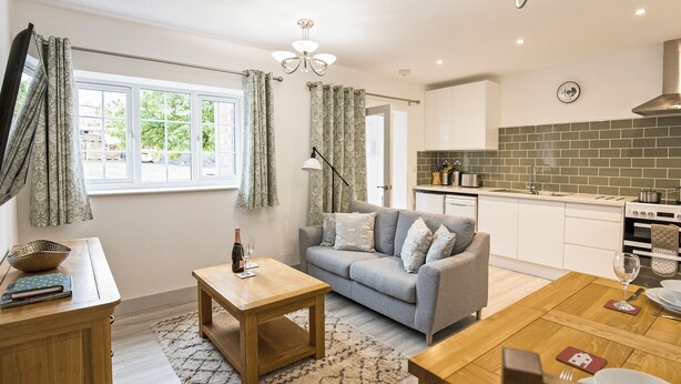 A modern kitchen with white cabinets, a green-tiled backsplash, and a built-in oven. - 1 bedroom accommodation in Ledbury (Ledbury)