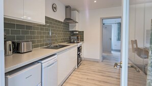 A modern kitchen with white cabinets, a stainless steel toaster, and a dishwasher. - 1 bedroom accommodation in Ledbury (Ledbury)