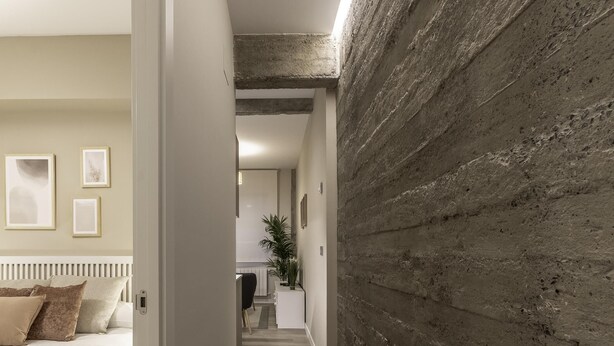 A hallway with a bed on the left, a textured wall on the right, and a staircase leading to another room. - Recién reformado junto a metro San Mamés (Bilbao)