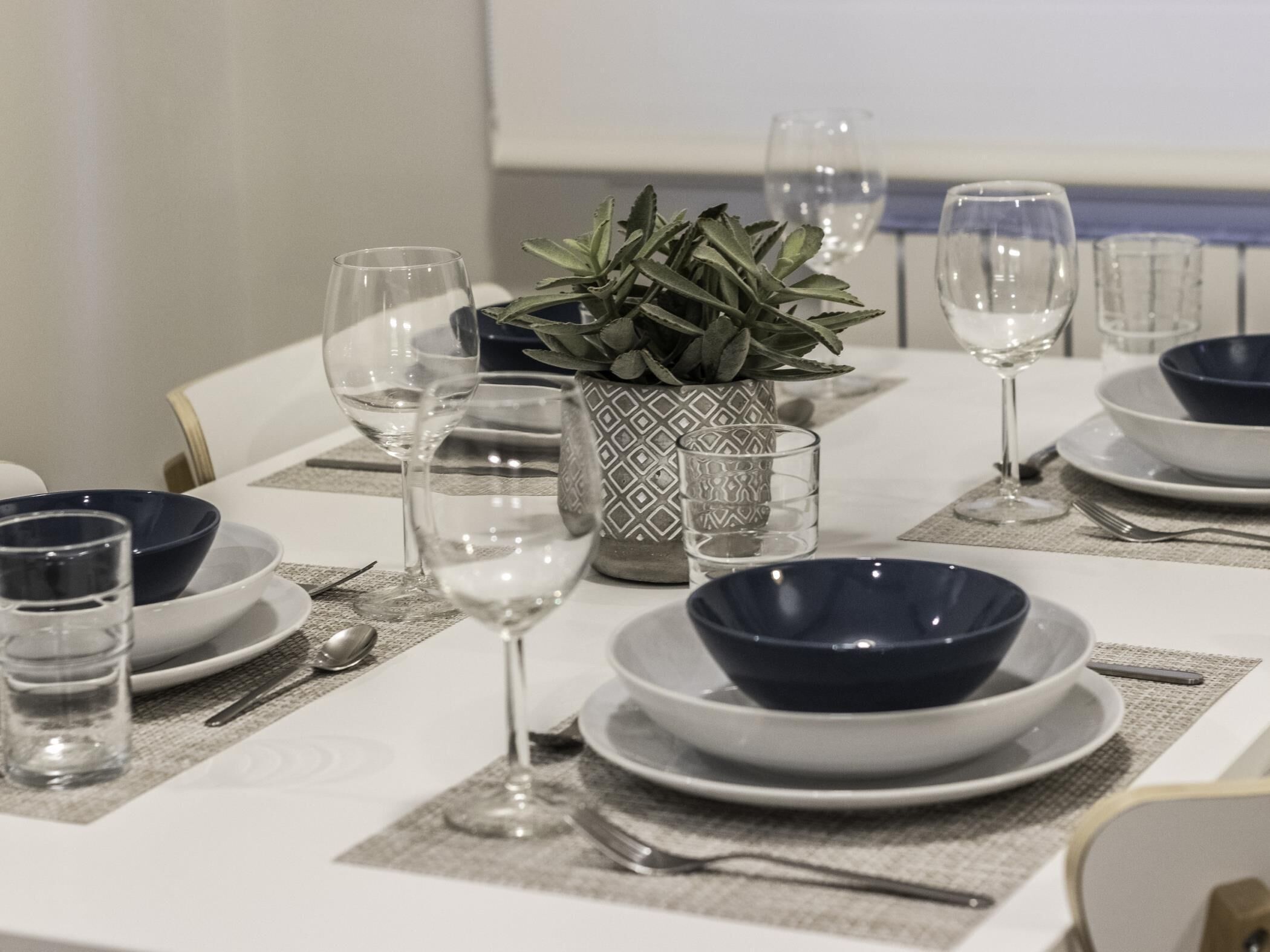 A dining table set with plates, bowls, glasses, and cutlery.