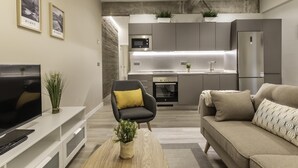 A modern living room with a flat-screen TV, a sofa, a coffee table, and a small plant. - Recién reformado junto a metro San Mamés (Bilbao)