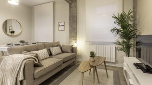 A modern living room with a sofa, a small wooden table, and a potted plant. - Recién reformado junto a metro San Mamés (Bilbao)