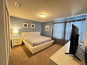 A bedroom with a bed, a nightstand, a lamp, a television, and a window with curtains. - Cozy, comfortable, fashion, elegant and luxurious holiday home (Kissimmee)