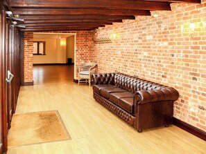 A room with a leather sofa, a wicker chair, and a brick wall.