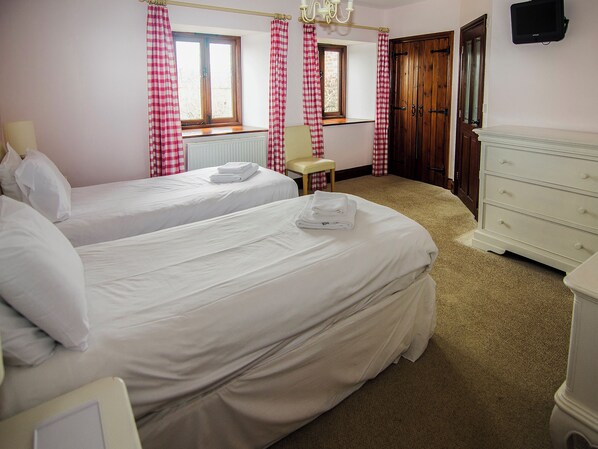 A hotel room with two beds, a chair, a dresser, and a window with curtains.