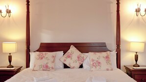 A neatly made bed with floral pillows, a wooden headboard, and two bedside lamps. - This charming barn conversion is ideal for a large family holiday. (Sculthorpe, Fakenham)