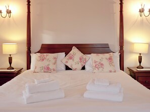 A neatly made bed with floral pillows, a wooden headboard, and two bedside lamps.