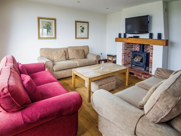 A living room with a fireplace, two sofas, a coffee table, and framed pictures on the wall.