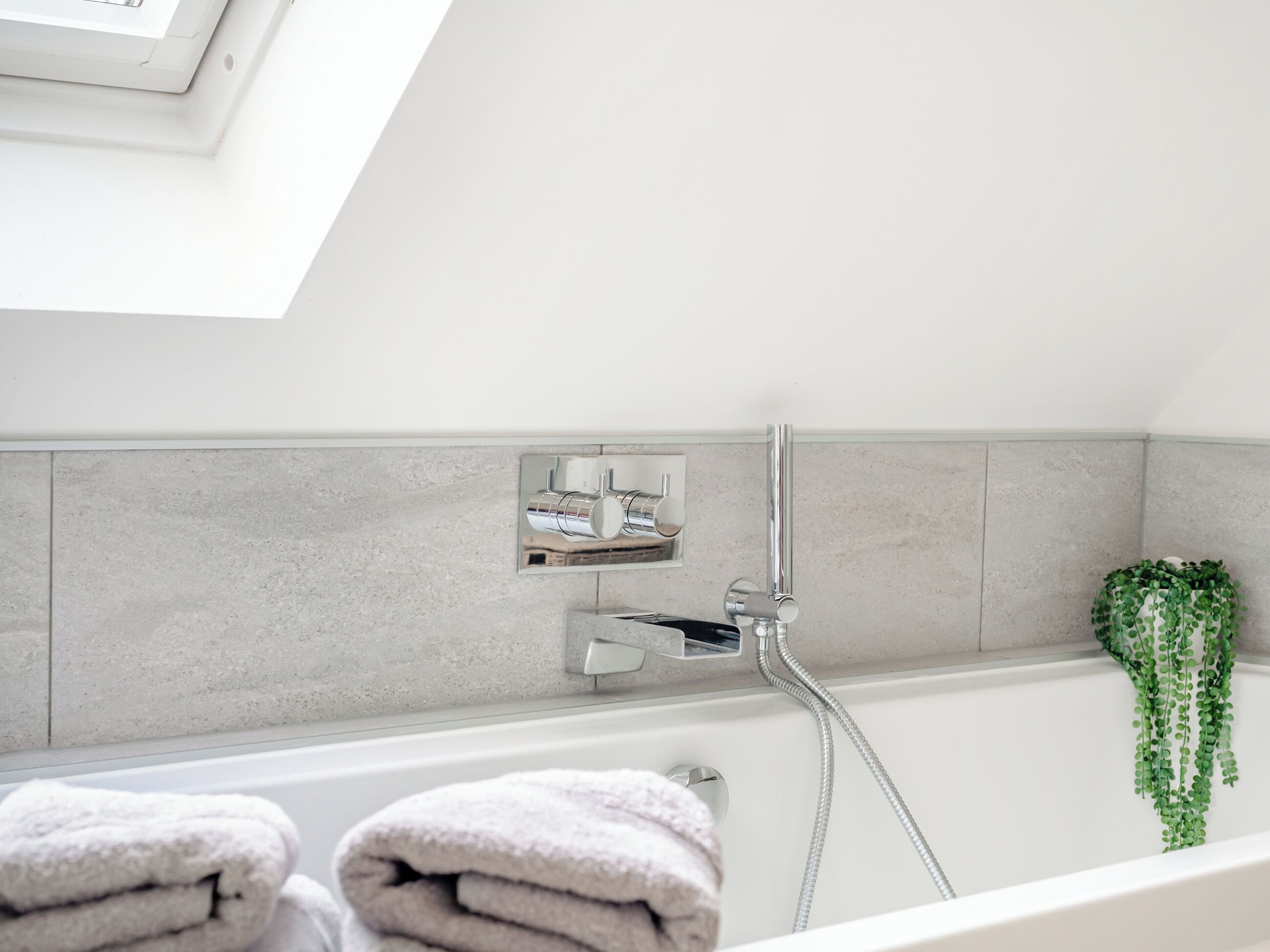 A modern bathroom with a bathtub, a shower, and a towel rack.