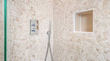 A bathroom with a mosaic wall, a shower, and a small window.