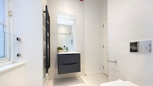 A modern bathroom with a white sink, a mirror, and a white toilet. - Trendy Studio on Rose South (Edinburgh)