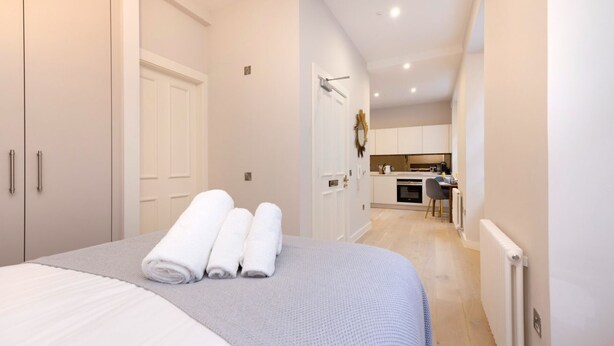 A bedroom with a bed, a bathroom, and a kitchenette. - Trendy Studio on Rose South (Edinburgh)