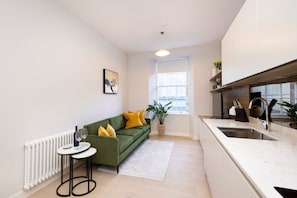 Relax in this cozy living space with a kitchenette, featuring a sofa, dining table, and city view.