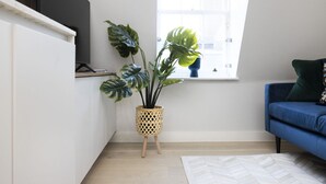 Una sala de estar moderna con un sofá azul, una planta en maceta y una ventana con vistas.
