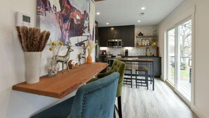 A modern kitchen with dark cabinets, a wooden countertop, and a dining area with a wooden table and two chairs.
