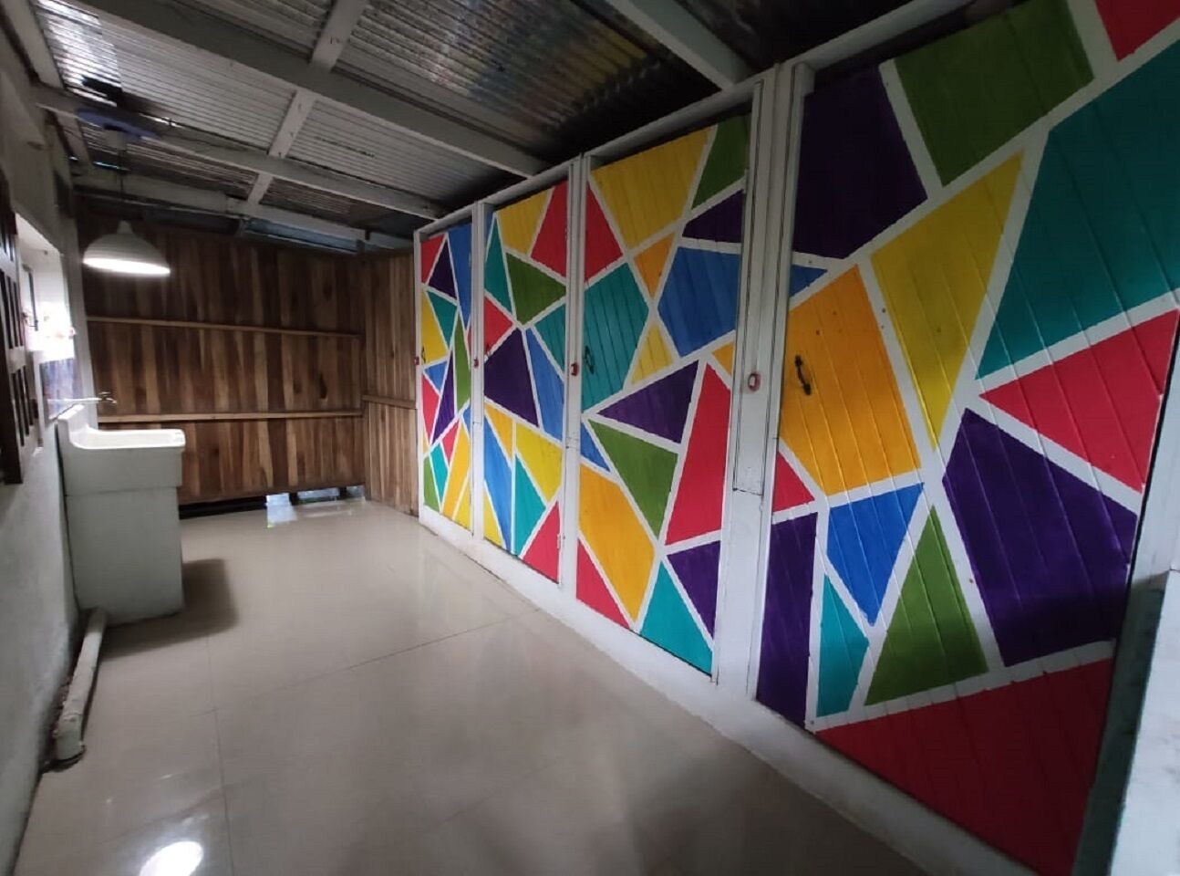 A hallway with a tiled floor and a colorful geometric wall design.