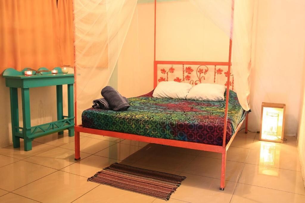 Uma cama com dossel, mesa de cabeceira e apoio para luminária.