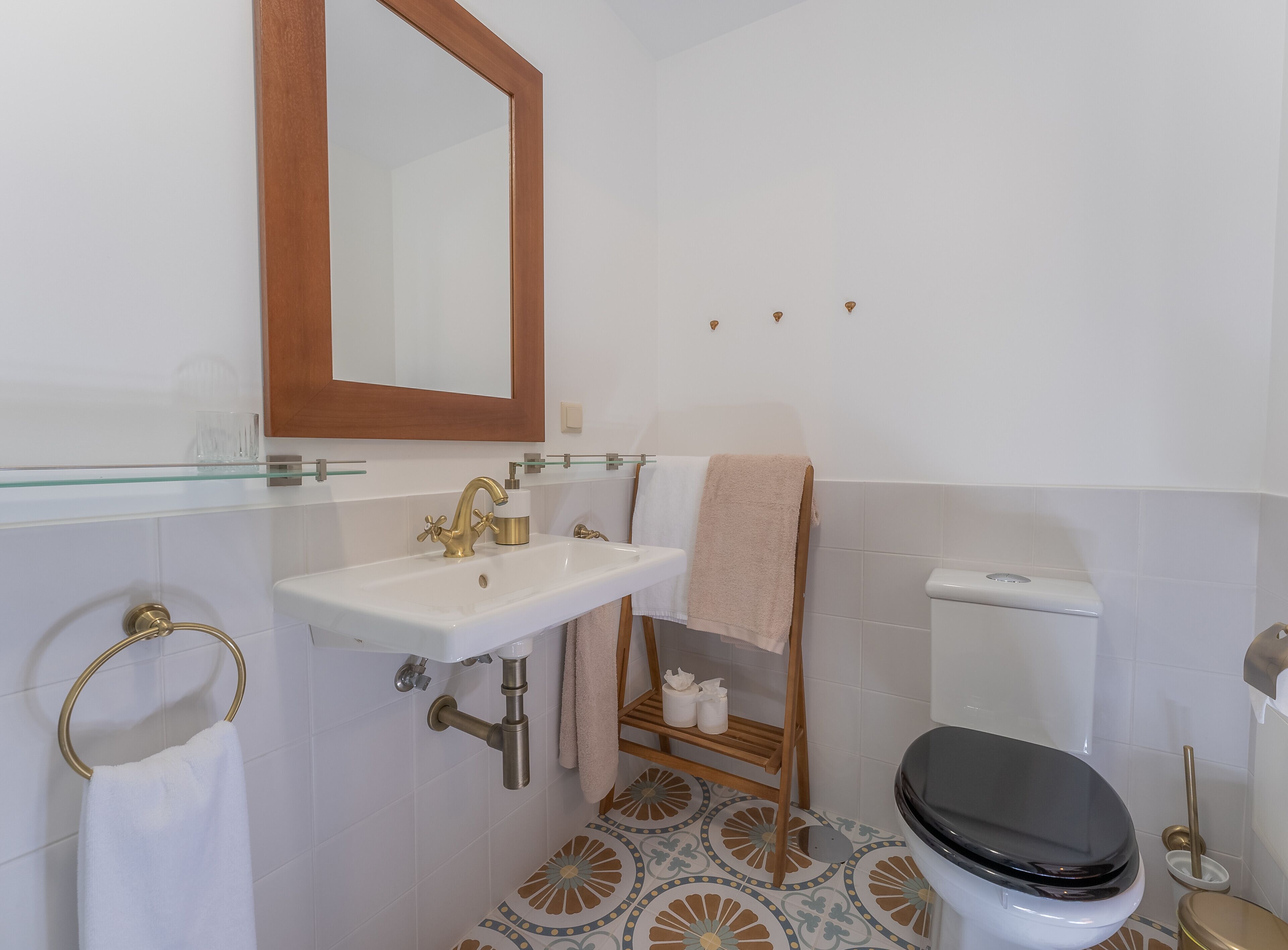 A bathroom with a white sink, gold faucet, and a toilet.