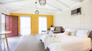 A bedroom with a large bed, a sofa, and a dining table. - Callala Calm - Pet Friendly - 5 Mins Walk to Beach (Callala Bay)