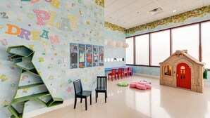 A children's playroom with alphabet wall decorations, a playhouse, and a window providing natural light. - Stunning 4 Bd Close to Disney Magic Village Resort 7537 (Kissimmee)