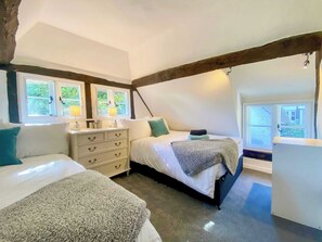 Een slaapkamer met twee bedden, een kapstok en een raam.