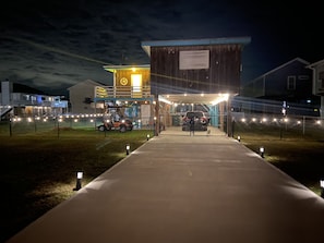 Welcome to a modern building with a prominent entrance, featuring a large illuminated sign and a secure fenced area.